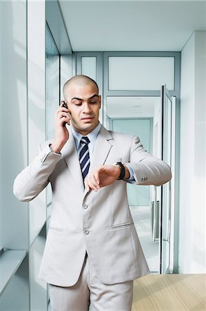 simsearch:630-06723232,k - Businessman talking on a mobile phone and checking the time Stock Photo - Premium Royalty-Free, Code: 630-06723217