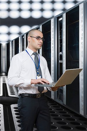 responsible technician - Technician working on a laptop in a server room Photographie de stock - Premium Libres de Droits, Code: 630-06723213