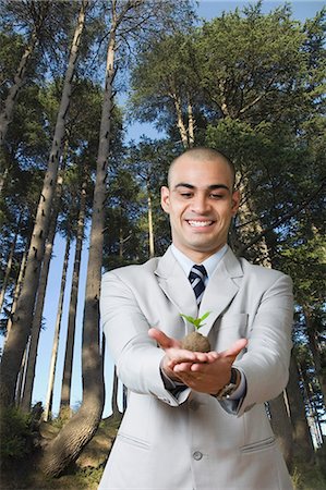 simsearch:630-06722068,k - Businessman holding a sapling and smiling Stock Photo - Premium Royalty-Free, Code: 630-06723220