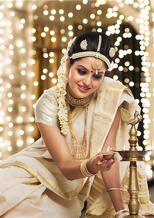 durga puja lady - Indian woman in traditional clothing lighting an oil lamp Stock Photo - Premium Royalty-Free, Code: 630-06723371