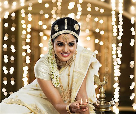 saari - Indian woman in traditional clothing lighting an oil lamp Stock Photo - Premium Royalty-Free, Code: 630-06723372