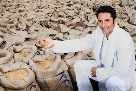 Man sitting near sacks of wheat and showing wheat grains, Anaj Mandi, Sohna, Gurgaon, Haryana, India Stock Photo - Premium Royalty-Free, Code: 630-07071182