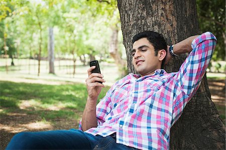 delhi - Man text messaging on a mobile phone in a park, Lodi Gardens, New Delhi, Delhi, India Foto de stock - Sin royalties Premium, Código: 630-07071366