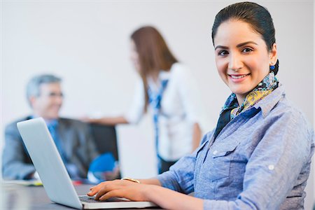 Portrait of a businesswoman working on a laptop with her colleagues in the background Stock Photo - Premium Royalty-Free, Code: 630-07071473