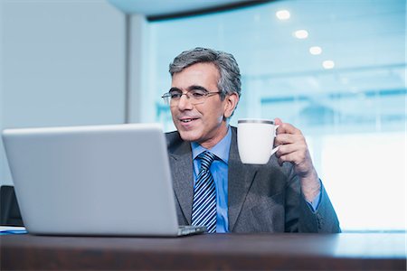 problem smile - Businessman working on a laptop and drinking coffee Stock Photo - Premium Royalty-Free, Code: 630-07071490