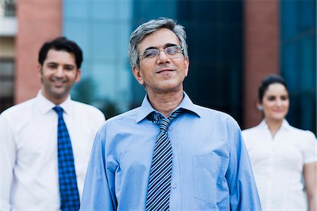 simsearch:630-07071521,k - Portrait of a businessman with his colleagues standing behind him Foto de stock - Sin royalties Premium, Código: 630-07071523