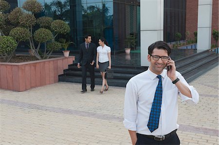 simsearch:630-07071521,k - Businessman talking on a mobile phone with their colleagues in the background Stock Photo - Premium Royalty-Free, Code: 630-07071595