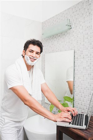 Man using a laptop while shaving his face Photographie de stock - Premium Libres de Droits, Code: 630-07071610