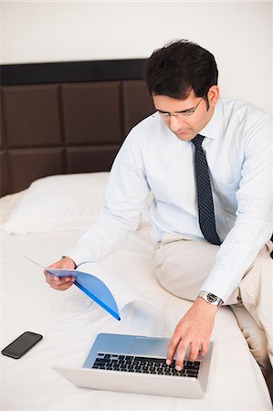 Businessman holding a file and working on a laptop Stock Photo - Premium Royalty-Free, Code: 630-07071629