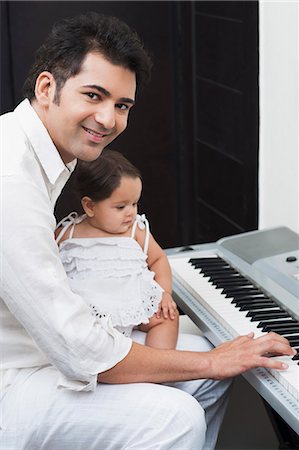 Man playing electronic piano with his daughter sitting on lap Photographie de stock - Premium Libres de Droits, Code: 630-07071655