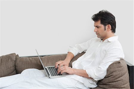 simsearch:400-04540351,k - Man reclining on a couch and working on a laptop Stock Photo - Premium Royalty-Free, Code: 630-07071660