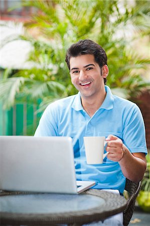 Man working on a laptop and holding a cup of coffee Stock Photo - Premium Royalty-Free, Code: 630-07071678