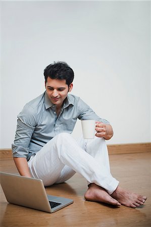 sitting on floor - Man drinking coffee and using laptop Foto de stock - Sin royalties Premium, Código: 630-07071693