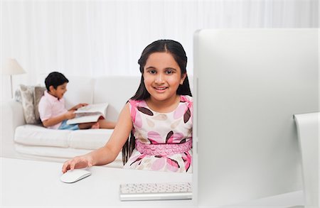 simsearch:630-07071840,k - Girl using a computer with her brother reading a book in the background Stock Photo - Premium Royalty-Free, Code: 630-07071747