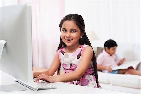 simsearch:630-07071840,k - Girl using a computer with her brother reading a book in the background Stock Photo - Premium Royalty-Free, Code: 630-07071749