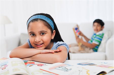 Girl reading books with her brother in the background Stock Photo - Premium Royalty-Free, Code: 630-07071757