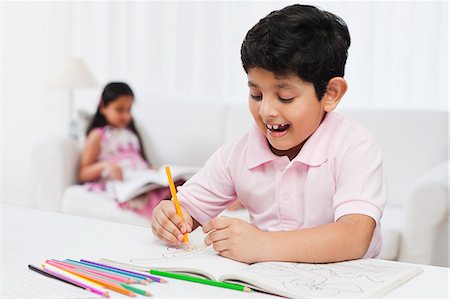 drawings of a girl and boy - Boy making drawings with his sister in the background Stock Photo - Premium Royalty-Free, Code: 630-07071752