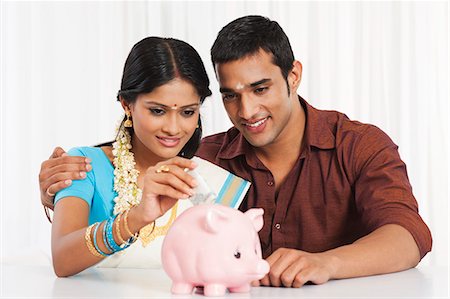 saari - South Indian couple putting cash in a piggy bank Stock Photo - Premium Royalty-Free, Code: 630-07071896