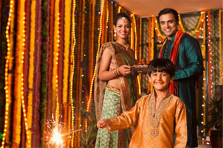 Boy burning fire crackers with his parents in the background on Diwali Stock Photo - Premium Royalty-Free, Code: 630-07072037