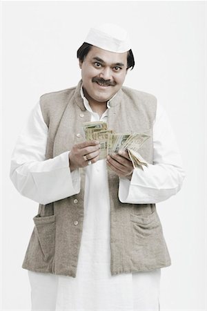 politician kurta and cap - Portrait of a male politician counting Indian currency Stock Photo - Premium Royalty-Free, Code: 630-01077105