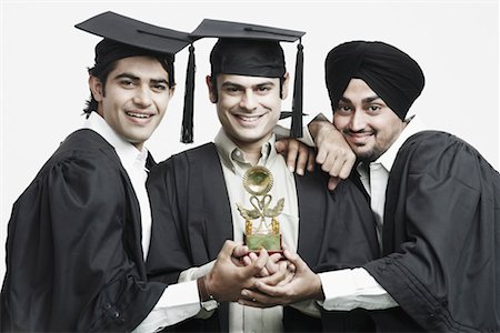 Portrait of three male graduates holding a trophy Stock Photo - Premium Royalty-Free, Code: 630-01077117