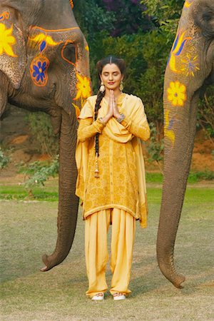 elephant indian costume - Young woman greeting in front of two elephants Stock Photo - Premium Royalty-Free, Code: 630-01077290