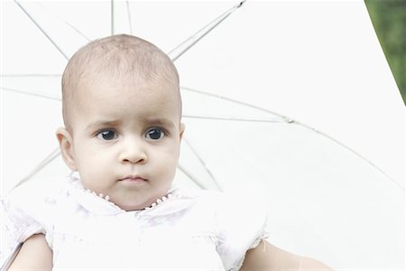 Close-up of a girl with an umbrella behind her Stock Photo - Premium Royalty-Free, Code: 630-01077938