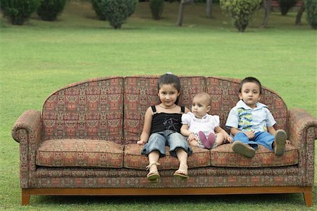 Three children sitting on a couch outdoors Stock Photo - Premium Royalty-Free, Code: 630-01077942