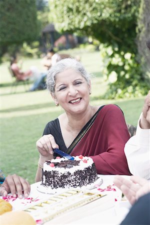 Portrait of a mature woman cutting a cake Stock Photo - Premium Royalty-Free, Code: 630-01077958