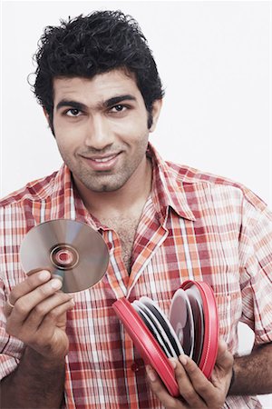 Portrait of a young man holding CDs and smiling Stock Photo - Premium Royalty-Free, Code: 630-01078589