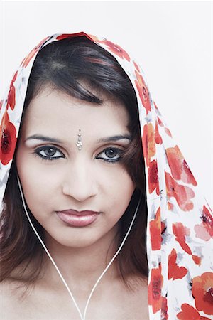 Portrait of a young woman with a stole on her head wearing headphones Stock Photo - Premium Royalty-Free, Code: 630-01078603