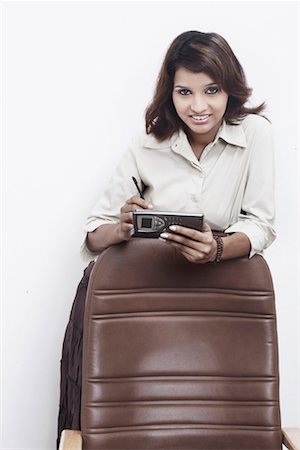 simsearch:630-01078178,k - Portrait d'une femme d'affaires s'appuyant sur une chaise, tenant un téléphone mobile Photographie de stock - Premium Libres de Droits, Code: 630-01078657