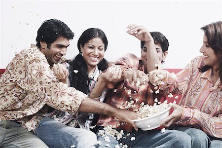 Close-up of two young couples sitting together on a couch eating popcorn Stock Photo - Premium Royalty-Free, Code: 630-01078769