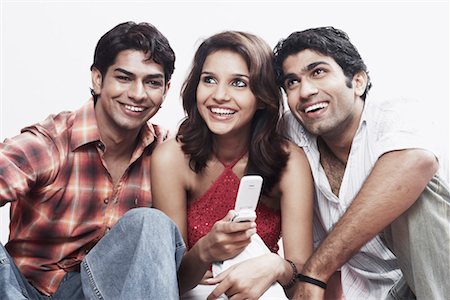 Close-up of a young woman and two young men smiling Stock Photo - Premium Royalty-Free, Code: 630-01078761