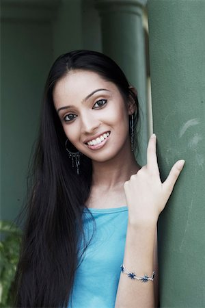 Portrait of a teenage girl leaning against a column smiling Stock Photo - Premium Royalty-Free, Code: 630-01078919