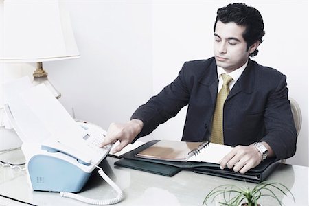 fax - Businessman sitting in an office using a fax machine Fotografie stock - Premium Royalty-Free, Codice: 630-01079929