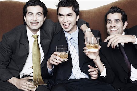Close-up of three young men holding glasses of whiskey Stock Photo - Premium Royalty-Free, Code: 630-01079983