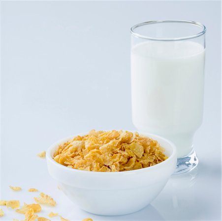 Close-up of a glass of milk with a bowl of corn flakes Stock Photo - Premium Royalty-Free, Code: 630-01126664