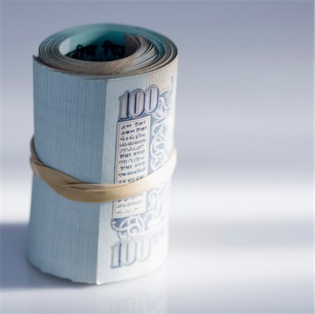 simsearch:630-01127338,k - Close-up of a rolled up bundle of Indian one hundred rupee banknotes bound with a rubber band Fotografie stock - Premium Royalty-Free, Codice: 630-01127133