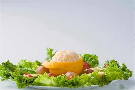 Close-up of a peeled orange with lettuce and baby corn on a plate Stock Photo - Premium Royalty-Free, Code: 630-01127257