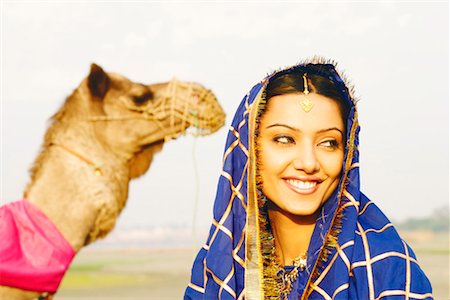 Close-up of a young woman with a camel in the background Stock Photo - Premium Royalty-Free, Code: 630-01127865