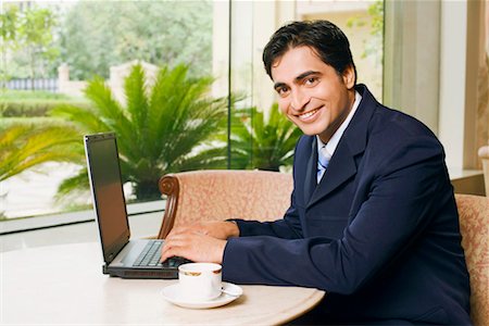 simsearch:630-01128454,k - Portrait of a businessman using a laptop in a cafeteria Stock Photo - Premium Royalty-Free, Code: 630-01128124