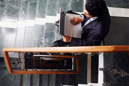 spiral staircase people - High angle view of a businessman sitting on the staircase and using a laptop Stock Photo - Premium Royalty-Free, Code: 630-01128336