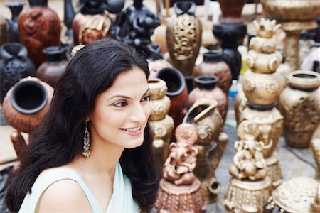 Side profile of a young woman smiling in a pottery store Stock Photo - Premium Royalty-Free, Code: 630-01128705