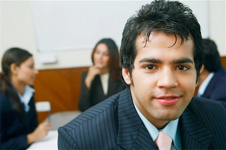 simsearch:630-01128982,k - Portrait of a businessman with three business executives sitting behind him Stock Photo - Premium Royalty-Free, Code: 630-01128772