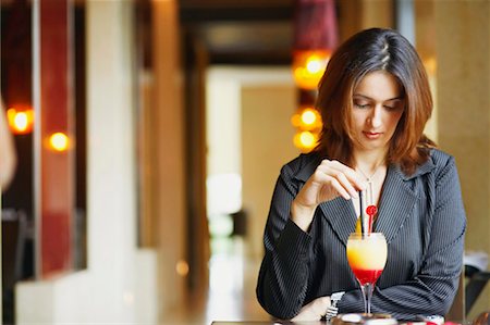 simsearch:630-01130529,k - Close-up of a businesswoman sitting in a restaurant with a glass of pinacolada Stock Photo - Premium Royalty-Free, Code: 630-01128874