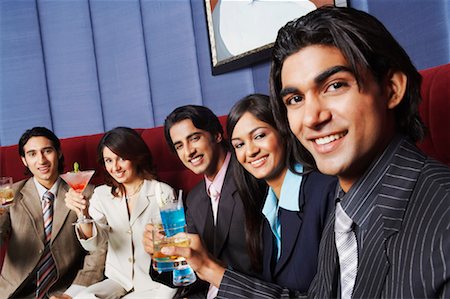 Portrait of two businesswomen and three businessmen sitting on a couch and holding glasses Stock Photo - Premium Royalty-Free, Code: 630-01128974