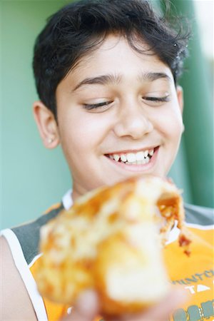 Close-up of a boy holding a slice of pizza Stock Photo - Premium Royalty-Free, Code: 630-01129699
