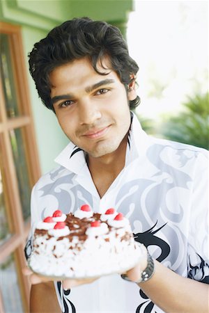 Portrait of a young man holding a birthday cake Stock Photo - Premium Royalty-Free, Code: 630-01129926