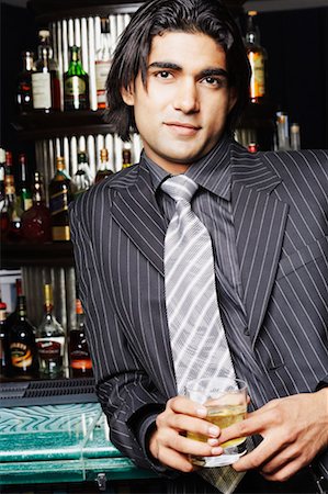 Portrait of a businessman holding a glass of whiskey at a bar counter Stock Photo - Premium Royalty-Free, Code: 630-01130406